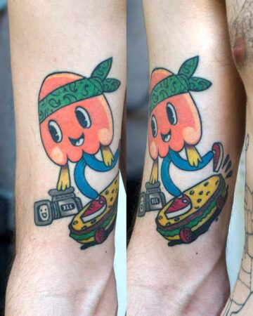 A vibrant tattoo of a cartoon mushroom character with a green bandana, riding a skateboard shaped like a burger. A film camera sits nearby. The tattoo is colorful and playful.