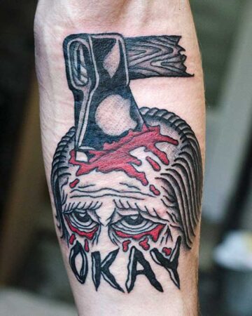 black and red tattoo on the arm on the forearm an ax in the head and the inscription okay