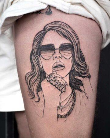 Line art tattoo of a woman with wavy hair and sunglasses on a thigh. She wears a "BABY" ring and layered necklaces, creating a bold, modern aesthetic.
