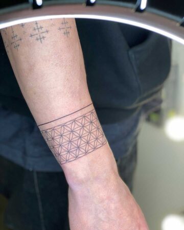 black and white tattoo on the arm on the wrist thin lines flower of life pattern ornament Indian bracelet around the arm