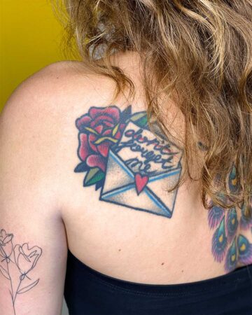 color tattoo on the shoulder blade on the back of a girl with the letter rose and heart