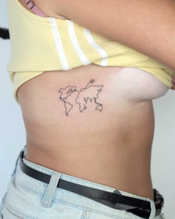 Minimalist world map tattoo on a woman's ribcage. The single-line design features an airplane above Asia, with the woman wearing a yellow top and denim shorts.