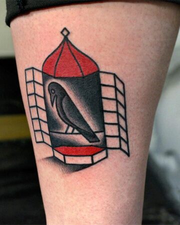 Tattoo of a bird inside a stylized birdcage. The cage is red and black with a geometric design.