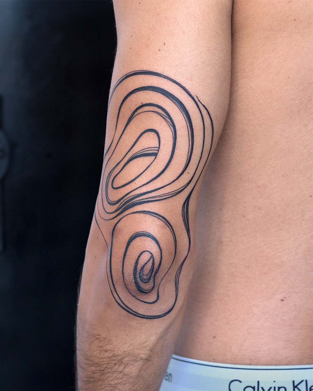 Abstract line art tattoo on an arm, featuring swirling shapes and curves. Body art inspiration. By tattoo artists in tattoo studio Canggu, Bali