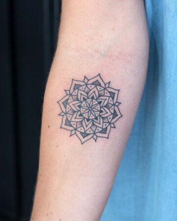 Geometric mandala tattoo on forearm with blue fabric background Done by tattoo artists in our fine line tattoo studio parlour shop Canggu, Bali