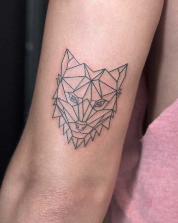 Geometric wolf tattoo on an arm. The minimalist line art depicts a wolf's head with sharp, angular shapes, creating a modern, stylized design.