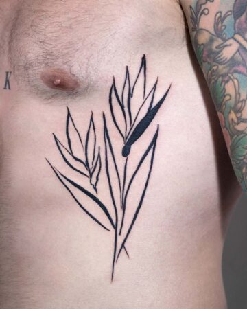 Minimalist botanical line art tattoo on a chest. The tattoo features a simple flower design, with black ink, and is a minimalist tattoo. Done by tattoo artists in our fine line tattoo studio parlour shop Canggu, Bali