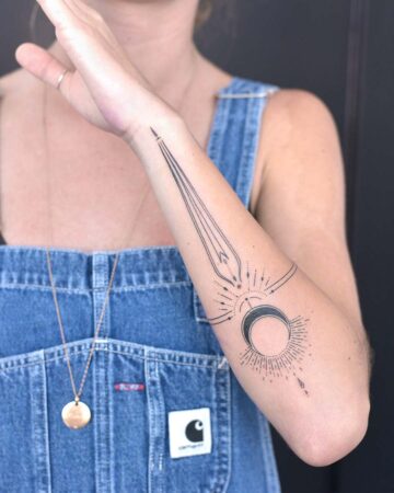 Intricate celestial tattoo featuring a crescent moon and sunburst design on a woman's forearm. The tattoo also includes linear elements, a band, and a teardrop. A stylish arm tattoo design. Done by tattoo artists in our fine line tattoo studio parlour shop Canggu, Bali