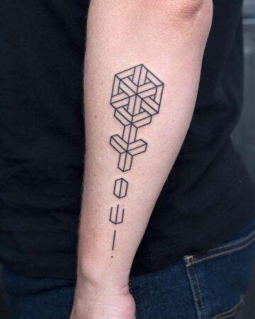 Geometric tattoo of a flower design on an arm, featuring a cube-like head and stem with abstract shapes. Below the flower are minimalist line art symbols. A minimalist arm tattoo design. Done by tattoo artists in our fine line tattoo studio parlour shop Canggu, Bali