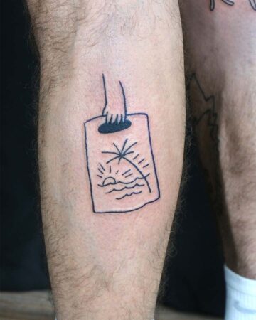 Minimalist travel tattoo on a leg featuring a hand holding a drawing of a beach with a palm tree, sun, and waves. Great inspiration for beach tattoos and minimalist tattoo ideas. Done by tattoo artists in our fine line tattoo studio parlour shop Canggu, Bali