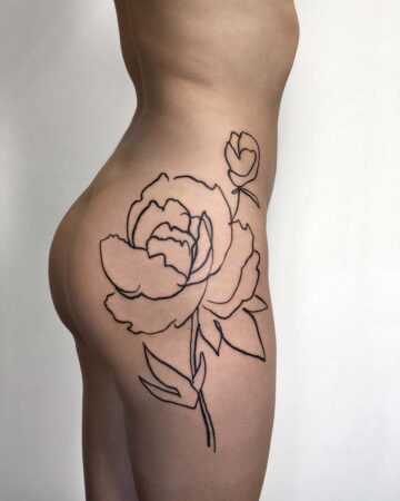 A minimalist peony tattoo on the side of a person's hip and thigh. The black line art tattoo features a large, open peony flower with a smaller bud and leaves, showcasing body art and floral tattoo design. Done by tattoo artists in our fine line tattoo studio parlour shop Canggu, Bali