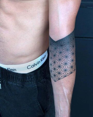 Close-up of a man's arm featuring a geometric tattoo design. The black ink tattoo, a geometric pattern, covers the forearm and fades into a solid black band at the top. It's a minimalist tattoo with a unique design, perfect for geometric tattoo inspiration. Done by tattoo artists in our fine line tattoo studio parlour shop Canggu, Bali