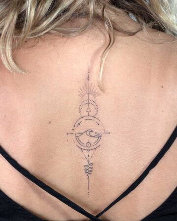A minimalist geometric tattoo on a woman's upper back features a wave design within a circle, with additional lines and dots leading to a sunburst and a symbol of infinity. This beautiful back tattoo is an example of a spiritual geometric tattoo. Done by tattoo artists in our fine line tattoo studio parlour shop Canggu, Bali