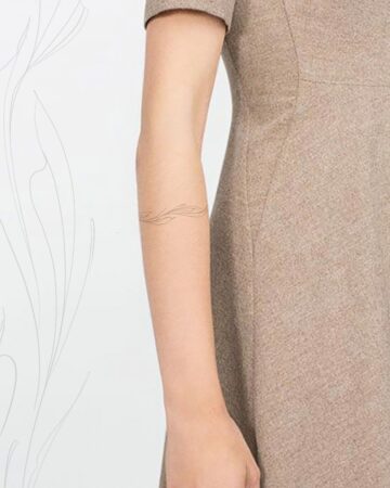 Close-up of a woman's arm in a beige dress with a minimalist tattoo Done by tattoo artists in our fine line tattoo studio parlour shop Canggu, Bali