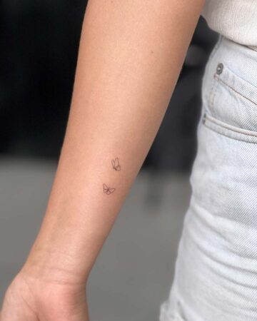 Three small butterfly tattoos on a woman's forearm. A minimalist tattoo design. By tattoo artists in tattoo studio Canggu, Bali