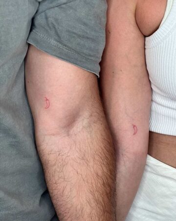 Couple's matching small red chili pepper tattoos on forearms, representing love and connection. By tattoo artists in tattoo studio Canggu, Bali