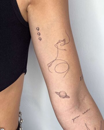 Minimalist line art arm tattoo featuring a face, Saturn, and numbers 999 & 11 By tattoo artists in tattoo studio Canggu, Bali