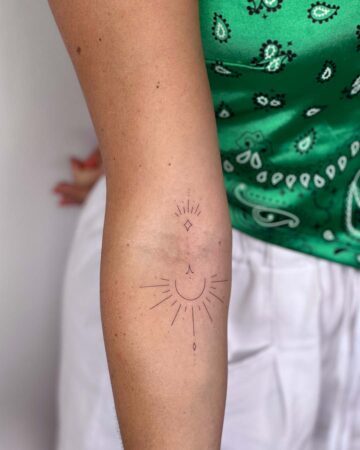 Minimalist sun and starburst arm tattoo design. Small sun tattoo with simple lines. By tattoo artists in tattoo studio Canggu, Bali