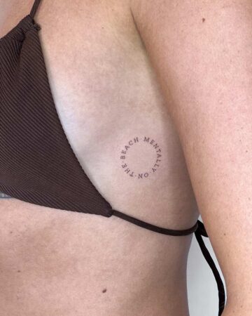 Minimalist tattoo on rib cage with text "Mentally on the beach By tattoo artists in tattoo studio Canggu, Bali