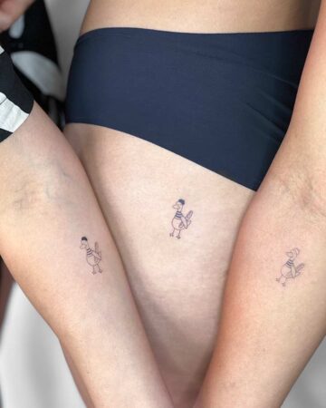 Three matching small tattoos of whimsical ducks on the arms and hip of three people, representing friendship. Each duck is drawn with a simple outline and wearing a hat. Perfect best friend tattoos. Done by tattoo artists in our fine line tattoo studio parlour shop Canggu, Bali