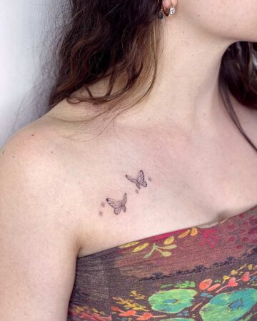 A woman's collarbone adorned with a delicate butterfly tattoo and tiny star accents. This small, minimalist design offers a beautiful example of a collarbone tattoo. Done by tattoo artists in our fine line tattoo studio parlour shop Canggu, Bali