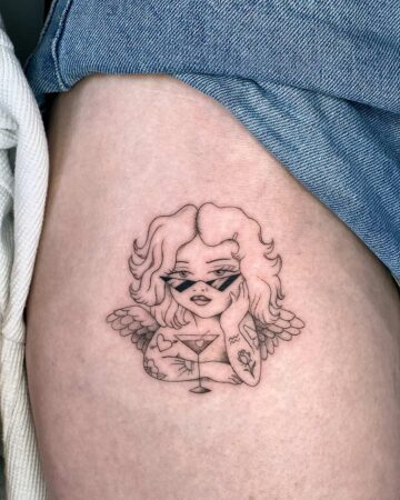 Angel tattoo design with wings and cocktail glass on thigh Done by tattoo artists in our fine line tattoo studio parlour shop Canggu, Bali