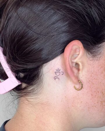 A minimalist tattoo behind the ear, featuring delicate line art. The tattoo is on the neck, next to a gold hoop earring. The skin has freckles. Done by tattoo artists in our fine line tattoo studio parlour shop Canggu, Bali