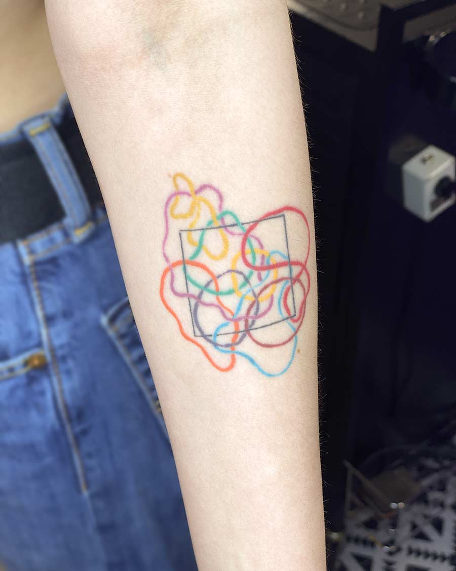 Colorful abstract arm tattoo featuring intertwined lines and a square shape. Minimalist tattoo design. By tattoo artists in tattoo studio Canggu, Bali