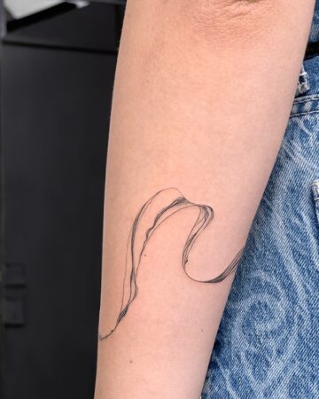 Fine line, minimalist tattoo of a flowing, abstract design on an arm. Simple arm tattoo design. Done by tattoo artists in our fine line tattoo studio parlour shop Canggu, Bali