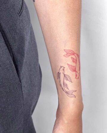 Minimalist koi fish tattoo in red and black ink on an arm, showcasing a simple yet elegant design. The arm tattoo features two koi fish swimming in opposite directions, a popular tattoo design. Done by tattoo artists in our fine line tattoo studio parlour shop Canggu, Bali