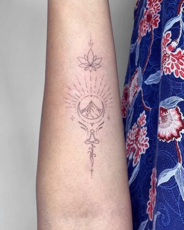 Delicate fine-line tattoo on an arm featuring a lotus flower, mountain within a crescent moon, and a meditating figure, symbolizing mindfulness and inner peace. A beautiful design perfect for a tattoo reflecting inner peace. Done by tattoo artists in our fine line tattoo studio parlour shop Canggu, Bali