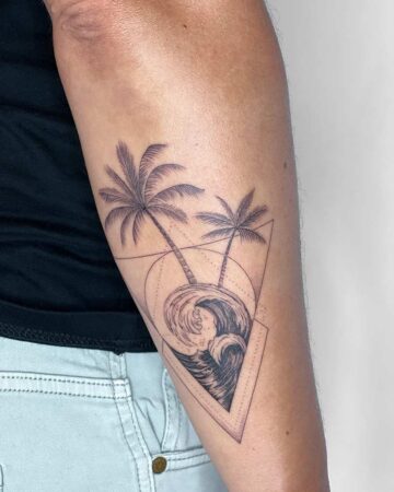 Minimalist beach tattoo design featuring two palm trees and a crashing wave within a geometric triangle. The black ink tattoo is on a person's forearm, capturing a serene coastal scene. Done by tattoo artists in our fine line tattoo studio parlour shop Canggu, Bali