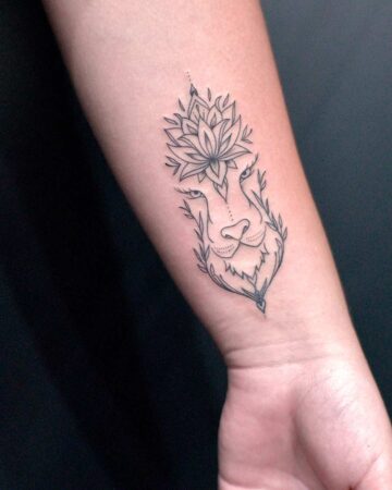 Fine line tattoo of a lion's face with a lotus flower design above its head, inked on a forearm.