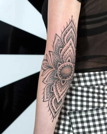Elaborate mandala tattoo design on a woman's arm, featuring intricate floral patterns and shading. The tattoo is placed near the elbow, showcasing a detailed floral design. Done by tattoo artists in our fine line tattoo studio parlour shop Canggu, Bali