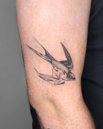 A detailed geometric swallow tattoo on an arm, showcasing modern art style. The bird features a combination of realistic shading and angular, geometric shapes, creating a unique body art design. Done by tattoo artists in our fine line tattoo studio parlour shop Canggu, Bali