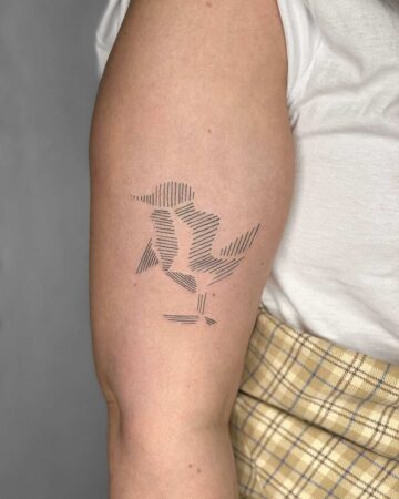 Minimalist line art bird tattoo on an arm, composed of parallel black lines. The tattoo depicts a bird perched on a branch, showcasing a clean and modern design. This minimalist tattoo is an example of line art. Done by tattoo artists in our fine line tattoo studio parlour shop Canggu, Bali