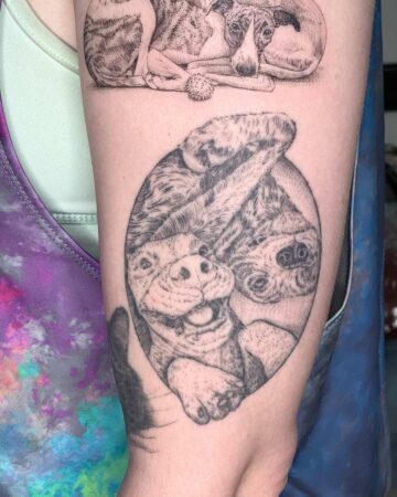 Detailed black and gray dog tattoo on an arm, featuring two playful dogs inside a circle. The tattoo artist's work showcases a pet portrait of a happy dog, part of a dog tattoo collection. Done by tattoo artists in our fine line tattoo studio parlour shop Canggu, Bali
