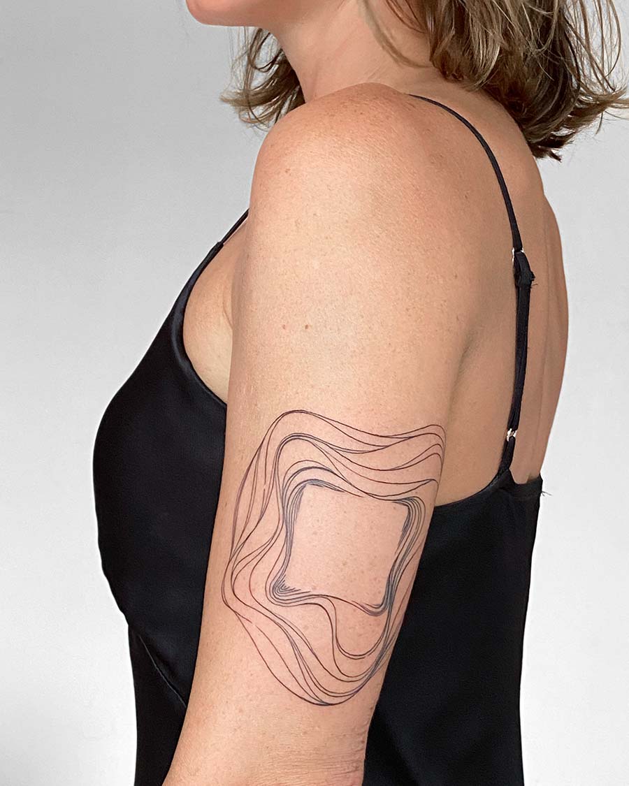 Woman's arm with a minimalist abstract tattoo design featuring wavy lines around a central square. The tattoo is an example of modern body art. Done by tattoo artists in our fine line tattoo studio parlour shop Canggu, Bali