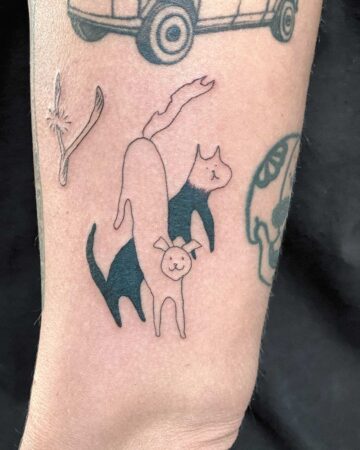 A minimalist pet tattoo featuring a black cat, a white cat, and a dog. The black cat is in front, with the white cat behind it, and a small dog in the middle. This cute pet tattoo is a great example of a minimalist dog tattoo. Done by tattoo artists in our fine line tattoo studio parlour shop Canggu, Bali