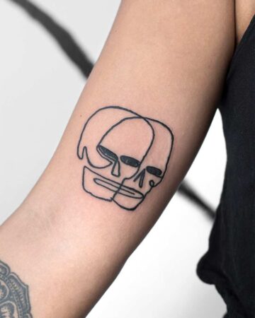 Minimalist line art tattoo of two overlapping skulls on an arm. The black ink design features a simple, modern style, perfect for a minimalist tattoo. Done by tattoo artists in our fine line tattoo studio parlour shop Canggu, Bali