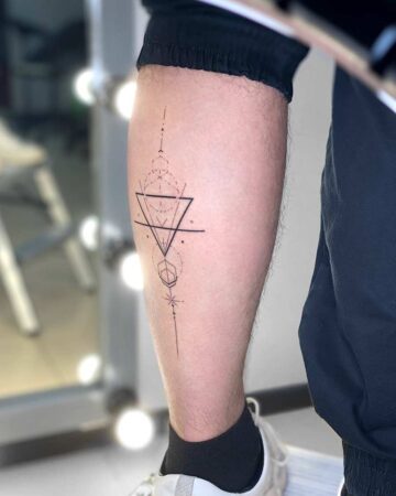 Geometric tattoo design on a leg, featuring a triangle, lines, and other shapes. A minimalist tattoo idea with a clean, modern aesthetic. The leg tattoo is a stylish example of geometric tattoo art. Done by tattoo artists in our fine line tattoo studio parlour shop Canggu, Bali