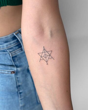 Delicate geometric tattoo on a fair-skinned arm, featuring a star-like design with lines and a circle. This minimalist tattoo is a great example of small tattoos and geometric tattoos. Done by tattoo artists in our fine line tattoo studio parlour shop Canggu, Bali