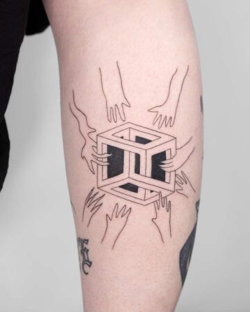 A geometric tattoo on a leg features an impossible cube held by multiple hands, a minimalist design using fine black lines. This tattoo, representing art and design, is a striking example of tattoo art. Done by tattoo artists in our fine line tattoo studio parlour shop Canggu, Bali
