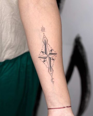 A minimalist compass tattoo on an arm, featuring a detailed geometric star, a diamond shape, and a crescent moon. This arm tattoo design is an example of a geometric tattoo style, perfect for compass tattoo inspiration. Done by tattoo artists in our fine line tattoo studio parlour shop Canggu, Bali
