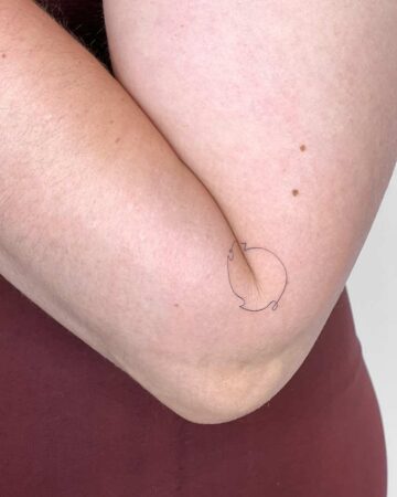 A minimalist line art tattoo of a simple shape on the inside of an elbow. The skin is fair with a few freckles. This is a minimalist tattoo idea for arm tattoos. done by artists in our fine line tattoo studio Canguu Bali