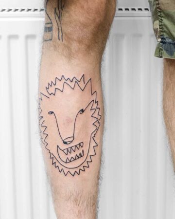A quirky, black line art tattoo of a wolf's face with jagged edges and a toothy grin on a leg, showcasing a unique tattoo design. Done by tattoo artists in our fine line tattoo studio parlour shop Canggu, Bali