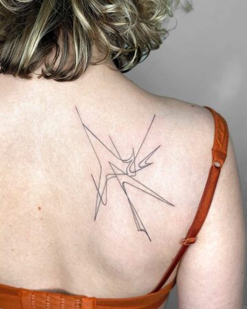 A woman's back with a minimalist tattoo design. The black fine line tattoo features an abstract, angular design on the upper back. The woman wears an orange bra strap. Done by tattoo artists in our fine line tattoo studio parlour shop Canggu, Bali