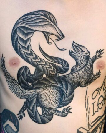 Black and gray dragon tattoo on a person's chest with intricate scales and shading Done by tattoo artists in our fine line tattoo studio parlour shop Canggu, Bali