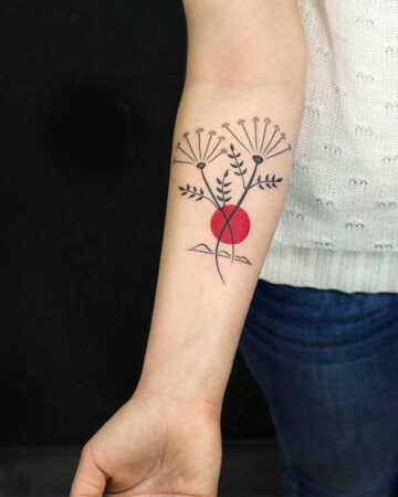 black and red tattoo on the arm on the forearm 2 flying flowers and the sun with a landscape