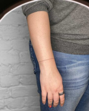 black and white tattoo on the arm on the wrist thin lines bracelet around the arm minimalism inscription in Morse Morse code